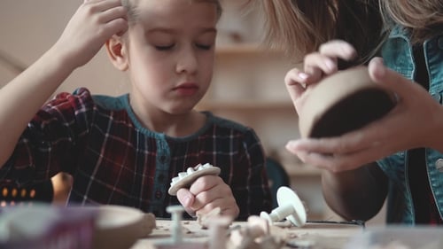 Girl and Adult Doing Crafts with Clay Indoors