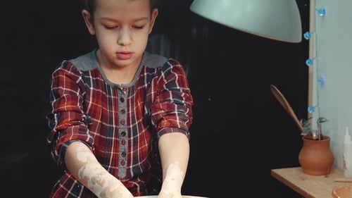Child Creates Pottery on Wheel with Help