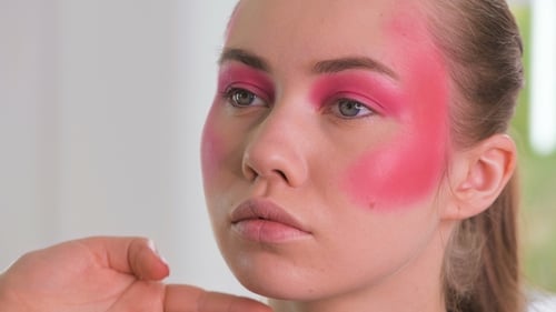 Applying Bright Pink Makeup To Young Woman's Face