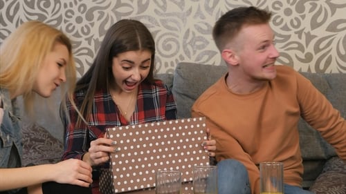 Belle jeune fille ouvre une boîte cadeau et est surprise et heureuse de ce qu'elle voit