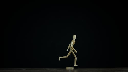 Running Wooden Figure Dummy Rotates in Studio on Black Background