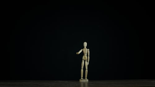 Stopmotion Wooden Figure Dummy Waving Arm in Studio on Black Background, Showing Goodbye