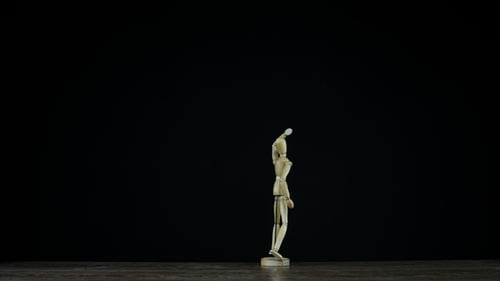 Wooden Mannequin Pivoting Against Black Background