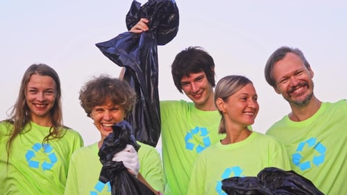 Five Young Volunteers in Green T-shirts with Image Recycle, Collect Garbage on an Oceanic Beach