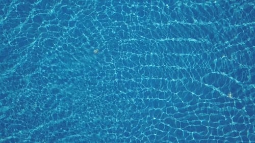 Pure Blue Water in the Swimming Pool with Light Reflections. Aerial Footage