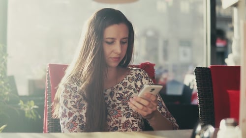 Woman Uses Cell Phone at Cafe Table