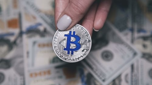 Ansicht von Silber-Bitcoins auf verschwommenem Hintergrund von 100-Dollar-Scheinen