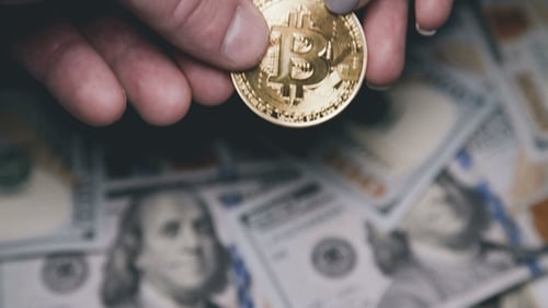Hands Holding Gold Bitcoin Coin Over Money