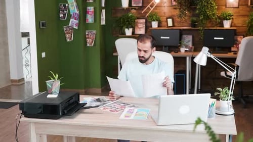 Focused Art Director in His Office Looking at His Designs