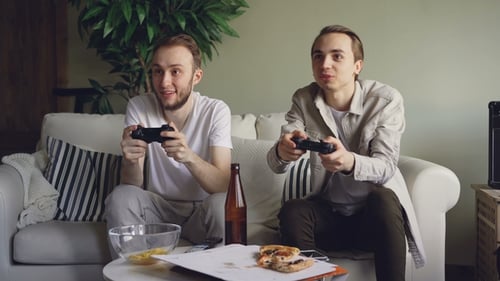 Young Men Play Video Games on the Couch