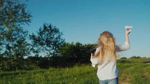 Girl Runs with Paper Airplane in Grassy Meadow