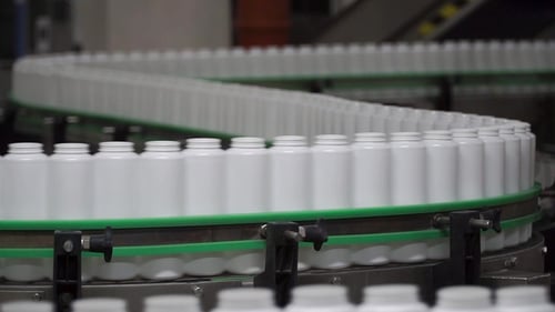 Concept d'usine et de recherche. Pince. Bouteilles en mouvement sur la chaîne de fabrication. Bouteilles en ligne