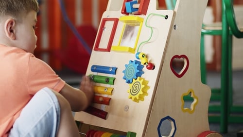 Toddler Plays with Colorful Wooden Activity Center