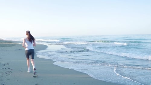 the Girl Is Engaged in Sports. She Runs From the Camera Along the Beach.