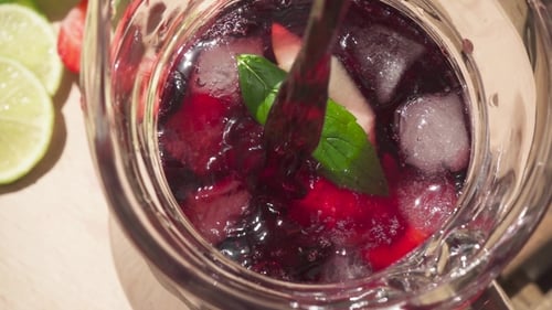 Red Beverage Poured into Pitcher with Fruit and Ice
