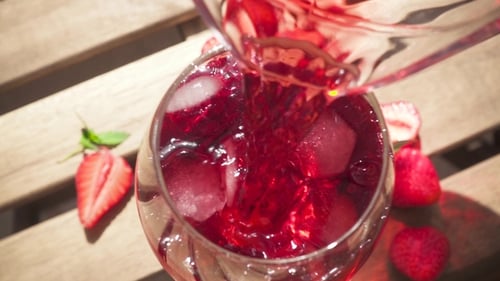 Red Drink Poured into Glass with Strawberries
