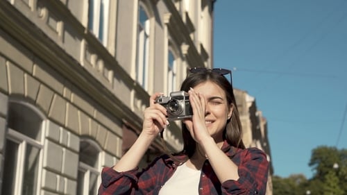 Young Woman Taking Picture with Film Camera in City