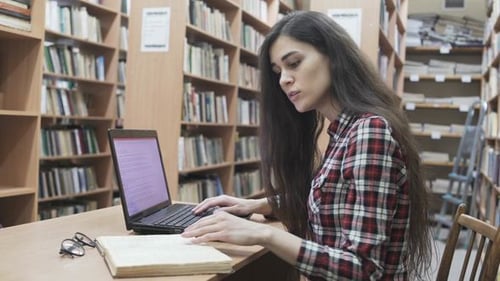 Étudiante dans une bibliothèque avec ordinateur portable
