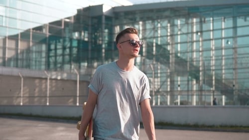 Young Adult Walking with Skateboard in Urban Setting