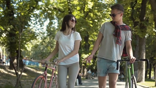 Couple Talking As Walking with Bikes