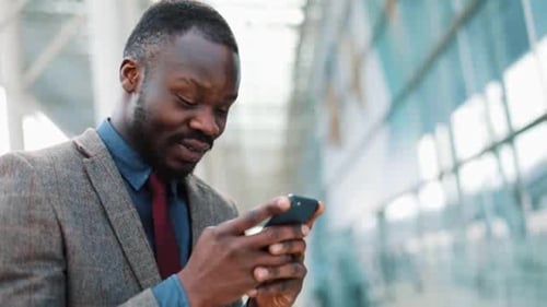 Young African Americanman Using App on Smartphone in City Near the Office Center Handsome Young