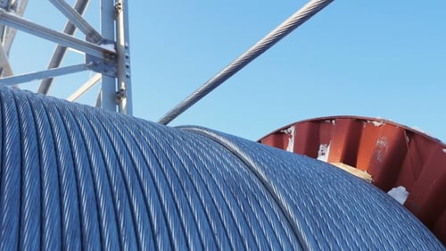 Drahtseil wickelt sich von der großen Spule gegen klaren Himmel ab