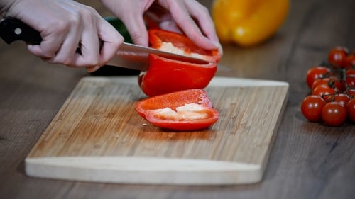 Woman cutting red bell pepper on cutting board
