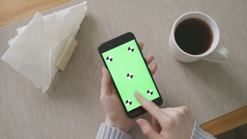 Junges Mädchen hält abends ein Smartphone mit Greenscreen