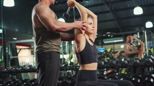 Coach teach Caucasian girl lift weight dumbbell for biceps to improve strength and maintain muscle.