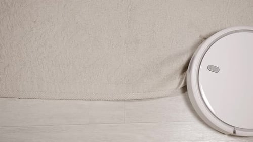 Weißer Roboter-Staubsauger reinigt den Teppich von oben