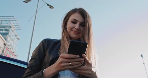 Young Woman Using Phone Near Charging Station