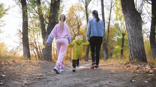 Mother and Two Children Walking in the Park and Enjoying the Beautiful Autumn Nature. Happy Family
