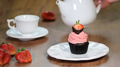 Pouring Tea Beside a Strawberry Topped Cupcake