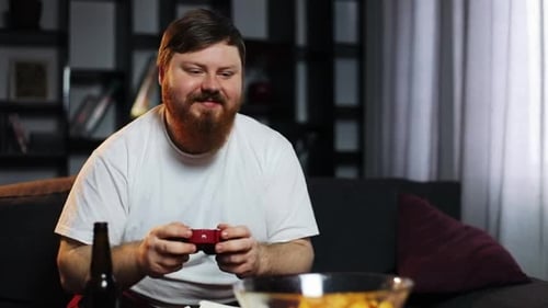 Bearded Adult Plays Video Game Relaxing on Couch
