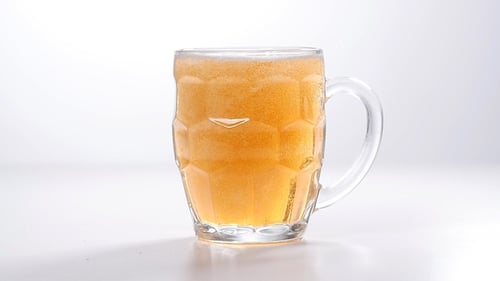 Pouring golden beer into a clear mug