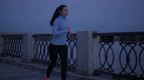 Woman Jogging at Night on Waterfront Path