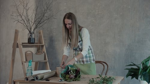 Fleuriste souriant arrangeant un bouquet de fleurs au