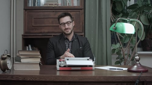 Man Types on Vintage Typewriter at Wooden Desk