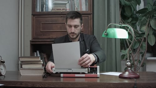 Man Types on Vintage Typewriter at Old Desk