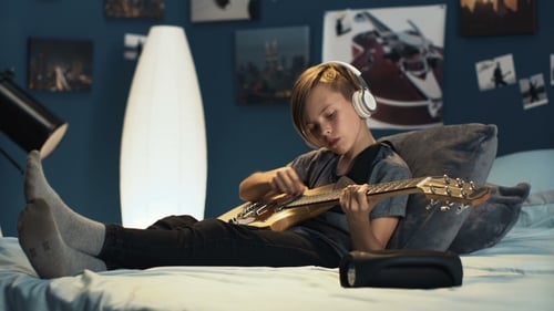 Teenager Playing Electric Guitar Lying on Bed