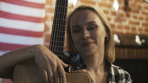 Woman Holding Guitar and Smiling Indoors