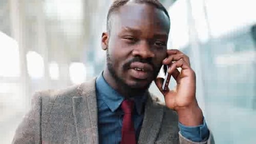 Serious Black Business Man Talking By Phone in the Street