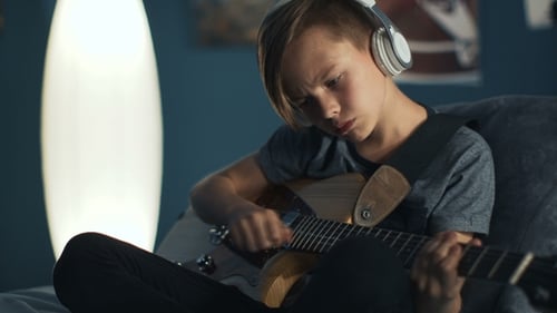 Boy Playing Electric Guitar with Headphones at Home