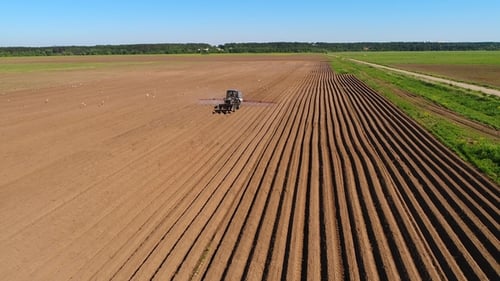 Landwirt auf einem Traktor besprüht gepflügte Felder mit Düngemitteln und Chemikalien