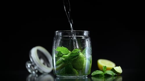 Clear Liquid Poured into a Jar with Limes