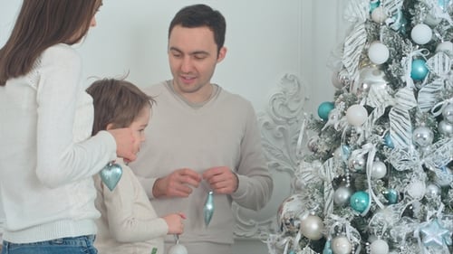 Family Decorates Christmas Tree with Ornaments at Home