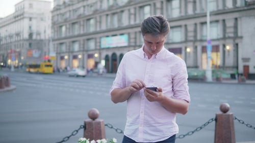 A Young Man Uses a Mobile Phone in the City.