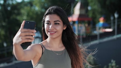 Smiling Woman Taking Selfie with Mobile Phone Outdoors