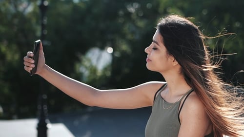 Woman with Long Hair Takes Selfie in Park
