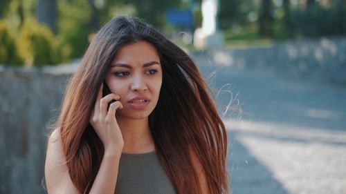 Worried Woman Talking on Cell Phone in Park